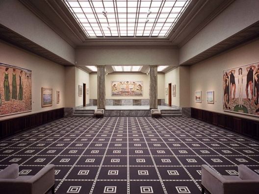 Light-filled elongated art exhibition hall with 4 armchairs