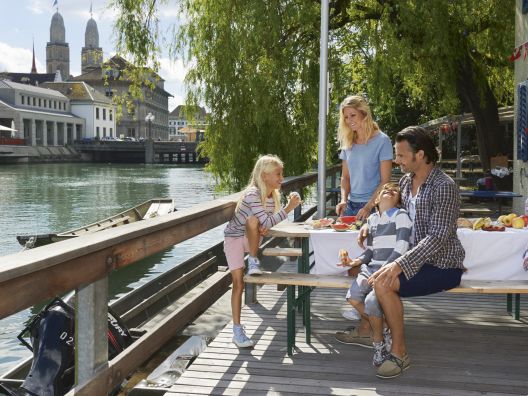 Family picnic on the Limmat with a view of the Grossmünster Church